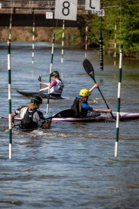 Drei Kanutinnen paddeln beim 1. Bergheimer Nachwuchslalom durch die Tore